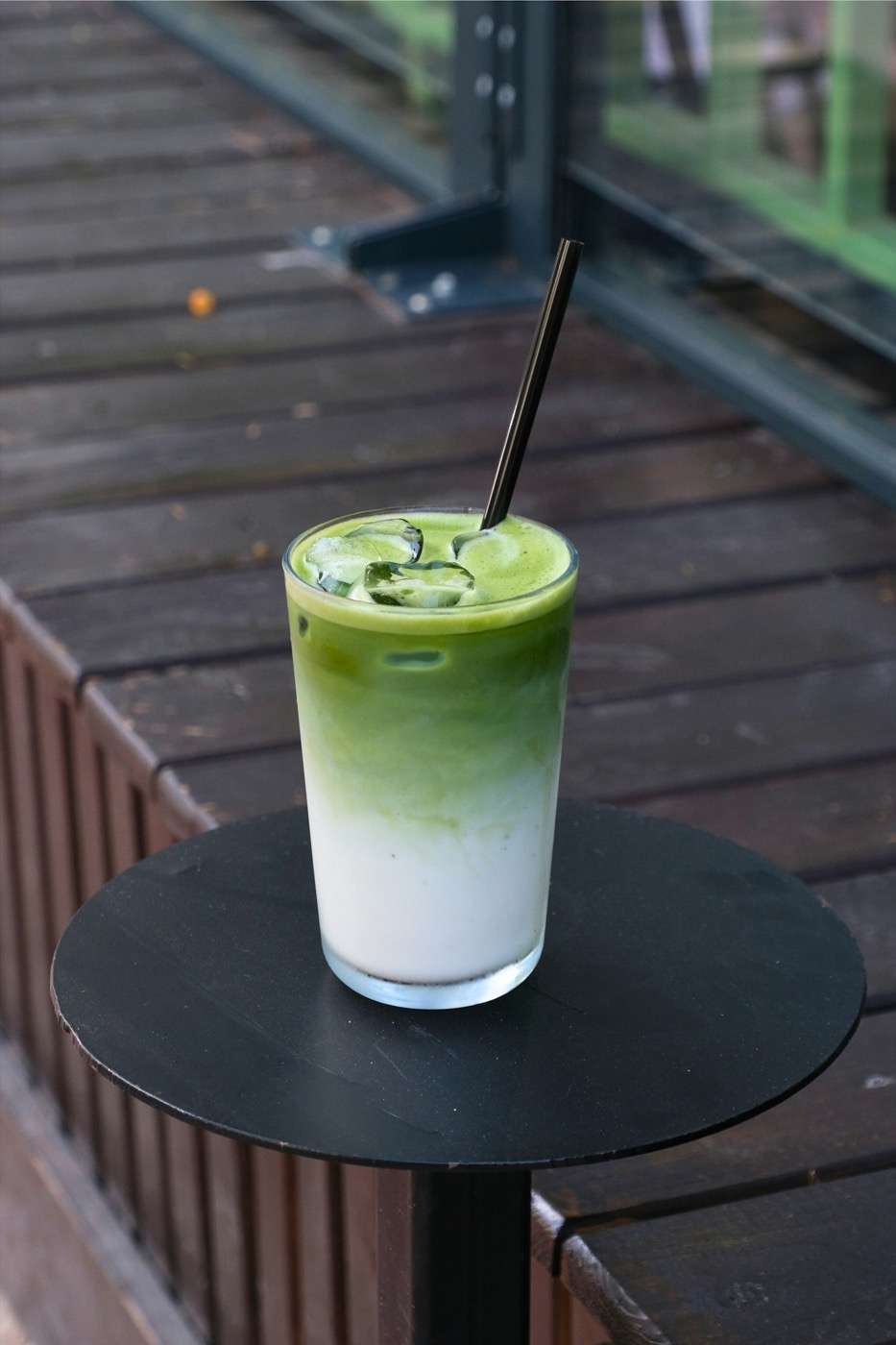 Ly matcha latte phân tầng xanh trắng trên bàn cà phê