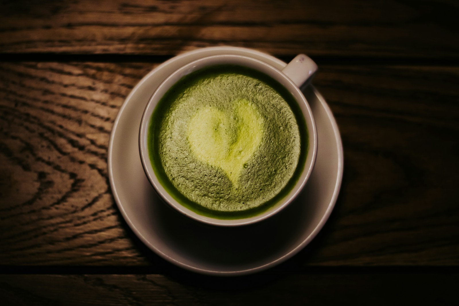 Tách matcha nóng đặt trên bàn gỗ, nhìn từ trên xuống