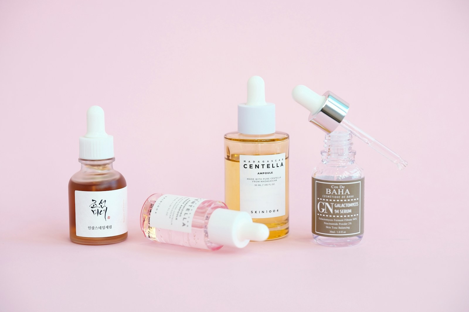 Các chai tinh chất dưỡng da của SEN Skincare trên nền hồng phấn
